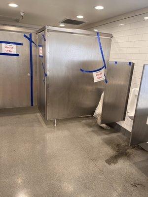 Front mens facilities in Harrisonville Walmart shown with one stall operational and urine all on the floor