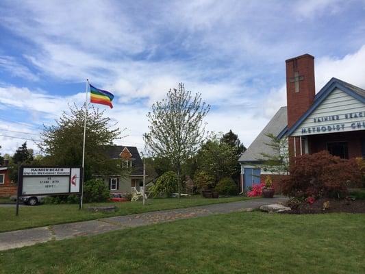 Message board, LGBT pride flag, and the front of the church.