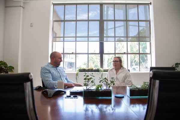 Two Oneupweb marketers chat in our main conference room on a sunny day.