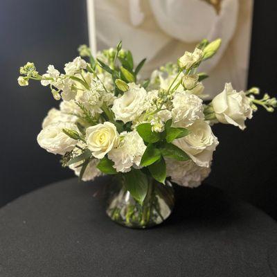 All white floral arrangement with hydrangea, roses, mini carnations, and lisianthus.