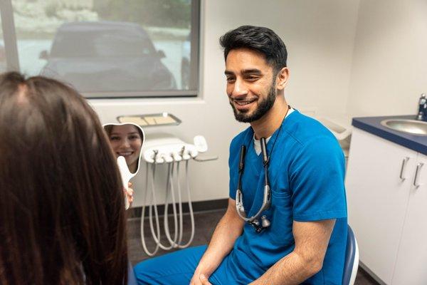 Dr. Siddiqui showing a patient their smile in the mirror at Advanced Family Dental of Midlothian