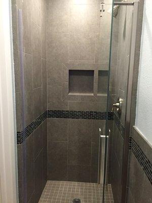 They built this shower from scratch - with a custom shower pan, soap niche, wainscoting and a perfectly assembled glass door.