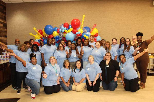 Staff pose in front of a balloon selfie station created for the Child & Adolescent Department Back-to-School Bash.