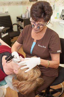 Barbara Denney applies permanent eyebrow pigment.