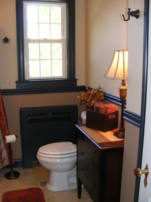 A modern bathroom complete with   a new table and lamp for extra counter space.