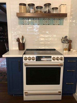 Giant spice rack on left of oven, custom knife drawer on top right w an open shelf on top of oven.