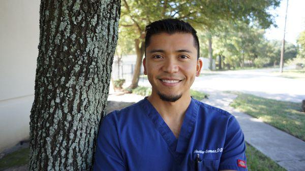 Dr. Hector M. Gomez posing by a tree outside his office