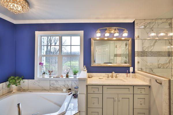 Master bathroom remodel with corner bathtub & marble lined tiles