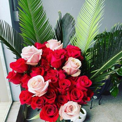 55 long stem roses with sago palm in tall vase