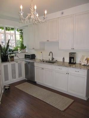 Crisp white cabinets enlarge a triangular kitchen.