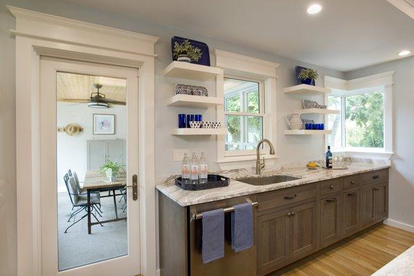 Comfortable and practical sink area with storage and windows to allow a plentiful amount of natural sunlight into the room