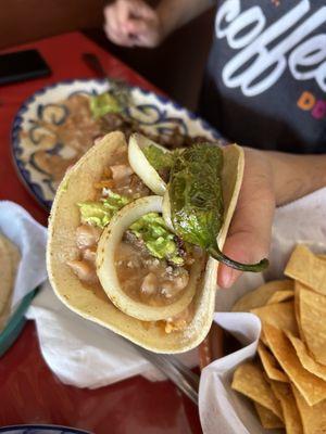 Taco w/ carne asada, beans, rice, topped with grilled onion rings & a jalapeno